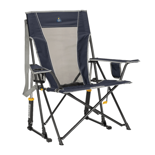 GCI Outdoor Comfort Pro Rocker folding camp chair in indigo, featuring a mesh back panel, padded armrests, a drink holder, and shock-absorbing rocker legs designed for outdoor use.